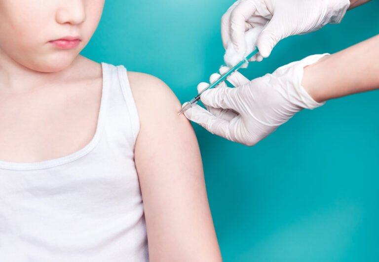 Doctor makes vaccination to a child. Inoculation in the shoulder