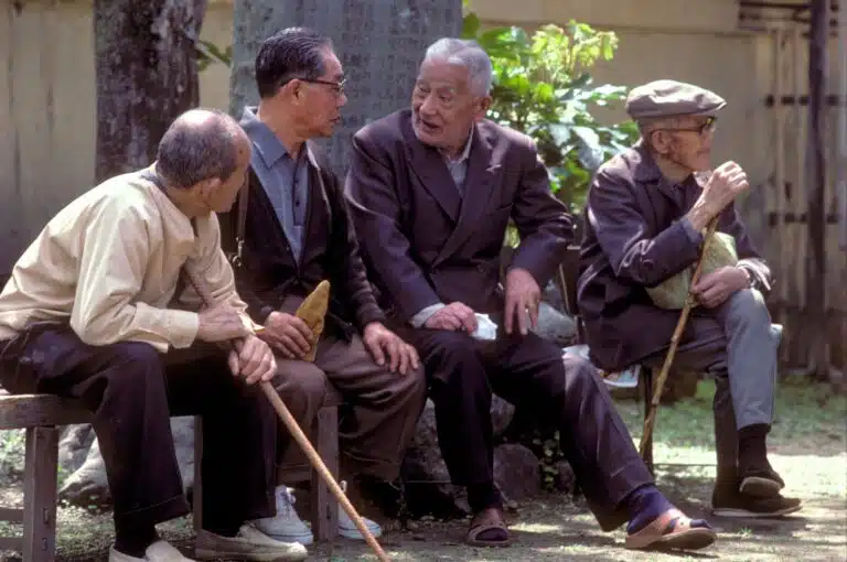 A group of elderly men sitting on a bench on a sunny day to discuss life in the past, present and future