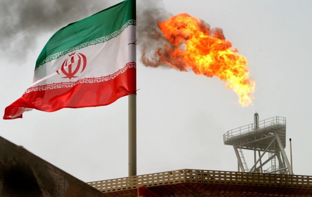 FILE PHOTO: A gas flare on an oil production platform is seen alongside an Iranian flag in the Gulf
