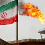FILE PHOTO: A gas flare on an oil production platform is seen alongside an Iranian flag in the Gulf